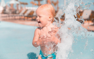 Toddler splashing in summer at a splash pad